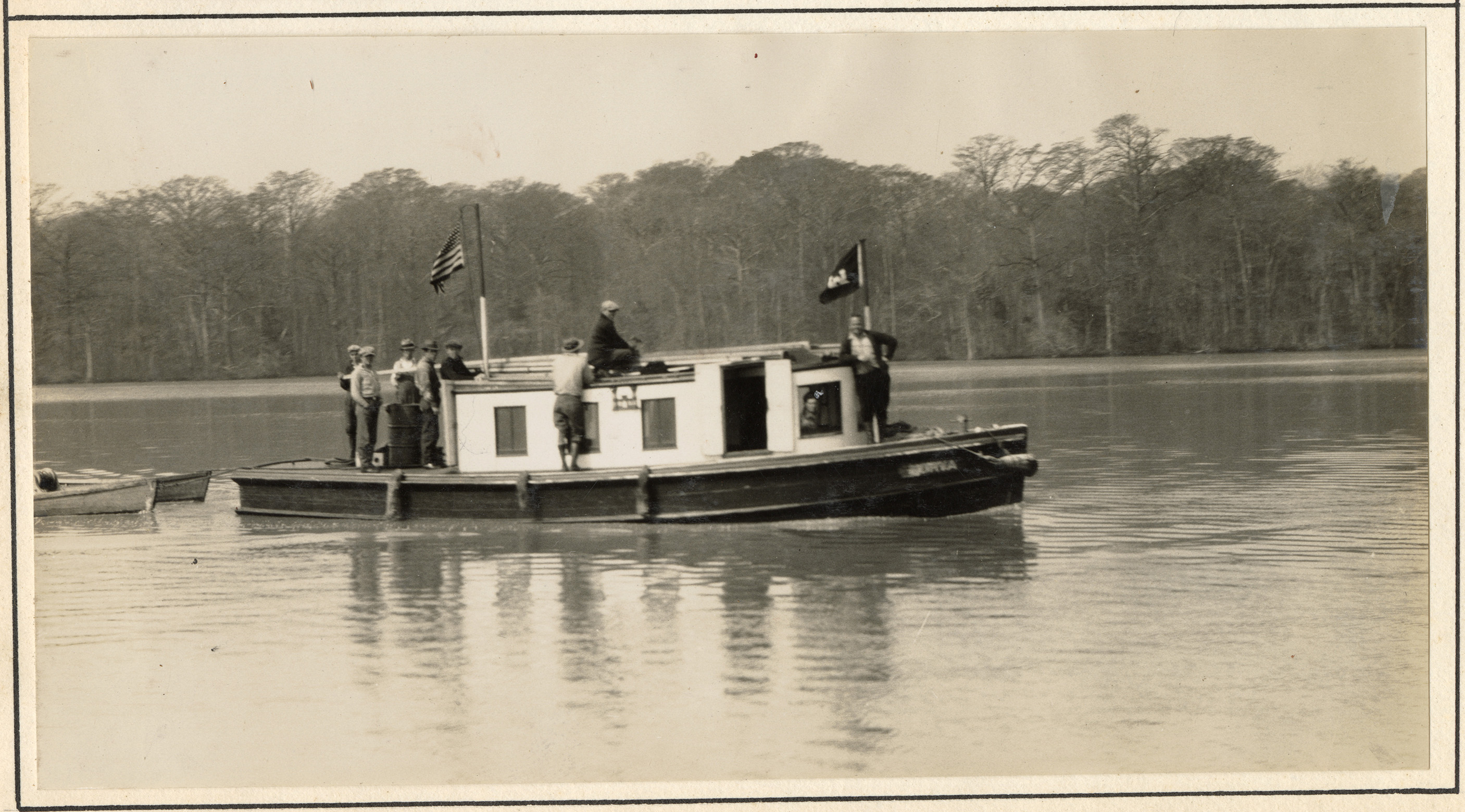 Small boat with crew of 5 on deck in calm water